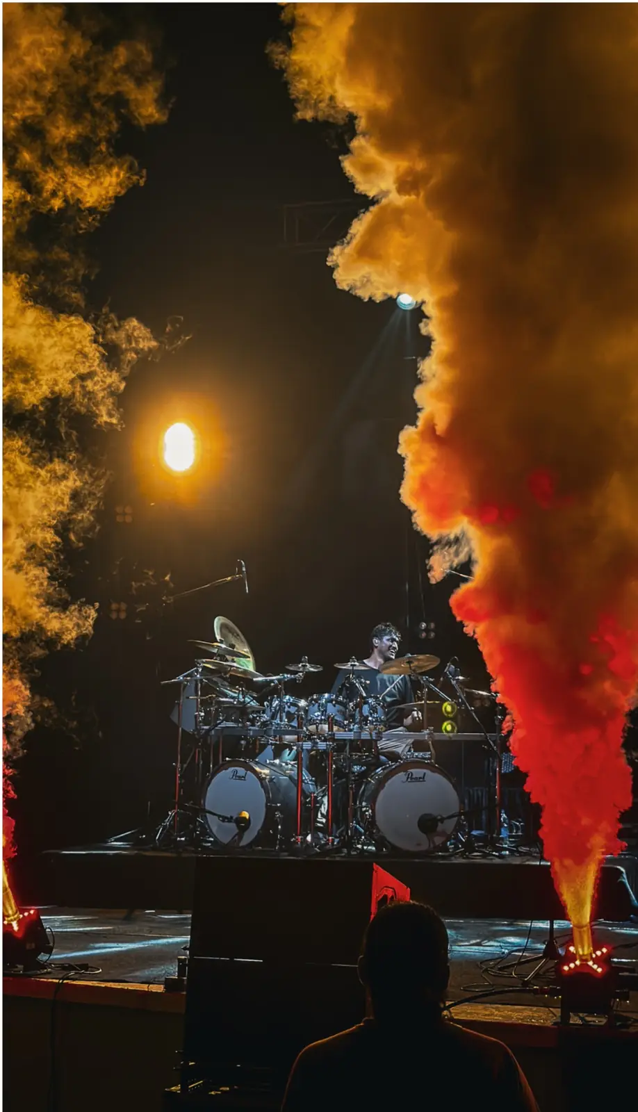 Yadhu behind the kit engulfed in orange and red stage smoke